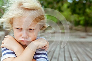 Face portrait of annoyed, unhappy caucasian kid with crossed arms photo