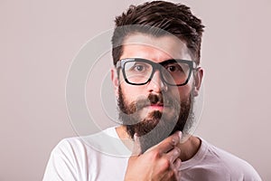 Face portrait of bearded man in glasses with hand on beard