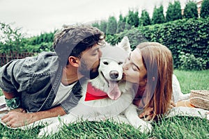 Face portrait of beautiful couple lovingly kissing a fluffy dog.