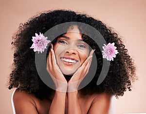 Face, portrait and black woman with flowers for hair care in studio isolated on a brown background. Floral cosmetics