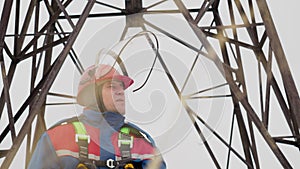 Face portrait of electrician standing on electrical tower background