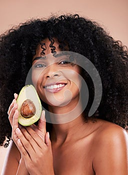 Face portrait, hair care and black woman with avocado in studio isolated on a brown background. Food, skincare and happy