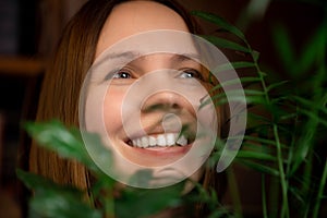 Face portrait of a middle aged woman in green plants smiling. A woman in her forties. Relaxation, calm state, happy face