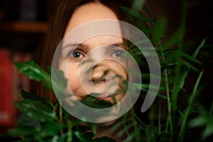 Face portrait of a middle aged woman in green plants smiling. A woman in her forties. Relaxation, calm state, happy face