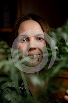 Face portrait of a middle aged woman in green plants smiling. A woman in her forties. Relaxation, calm state, happy face