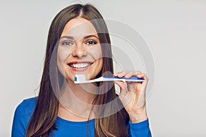 Face portrait of woman smiling with teeth holding toothy brush.