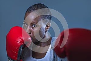 Face portrait of young angry and defiant black afro American sport woman in boxing gloves training and posing as a dangerous figh