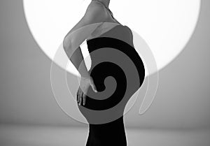 Without a face. A pregnant woman in a black tight dress.