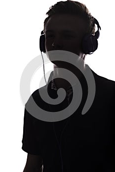 Face profile silhouette of music lover teenager listening to favorite song in headphones , handsome young man on white 