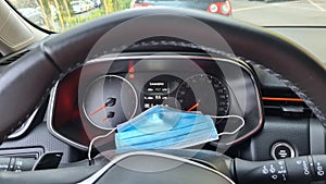 A face protection mask lay on a dashboard in a car