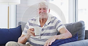 Face, relax and senior man with coffee on sofa happy, free and chilling at home on weekend. Smile, portrait and elderly
