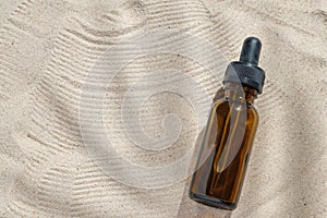 Face serum of glass bottle with a pipette on a natural background with sand. Essential oil for moisturizing body skin. mockup of