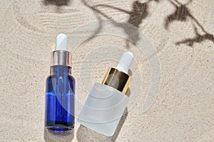 Face serum of glass bottle with a pipette on a natural background with sand. Essential oil for moisturizing body skin. mockup of