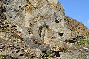 Face shape rock on cliff with textured layers and shapes.