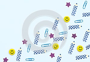 Face shaped yellow magnets, blue clips, pencil and star shaped paper stickers on white background. School and office supplies,