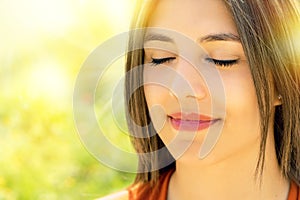 Face shot of relaxed woman meditating outdoors.