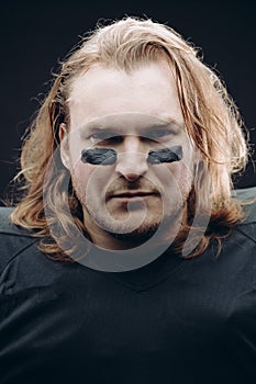 Determined American football player posing with painted face and chewing gum