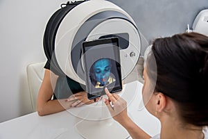 Face skin analyze system. Cosmetologist analyzing woman face.