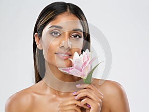 Face Skin Care. Beauty Indian Model smelling Lotus Flower. Beautiful Woman Portrait with Natural Make up and smooth Skin