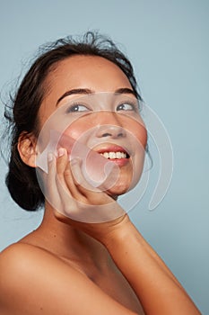 Face skin care. Smiling woman using oil blotting paper portrait