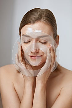 Face skin care. Woman applying facial cleanser on face closeup