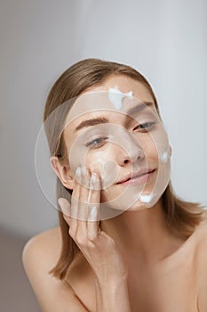 Face skin care. Woman applying facial cleanser on face closeup