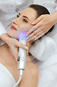 Face Skin Cosmetology. Closeup Woman Doing Blue Light Treatment