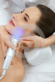 Face Skin Cosmetology. Closeup Woman Doing Blue Light Treatment