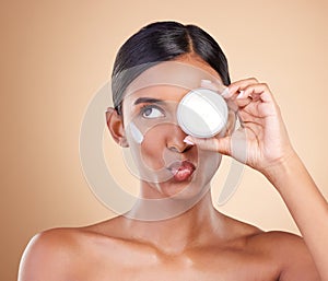 Face, skincare or Indian woman with cream for beauty or wellness isolated on studio background. Cosmetics or girl model