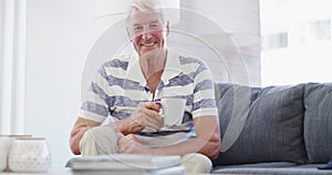 Face, smile and senior man with coffee on sofa relax, free and chilling at home on weekend. Happy, portrait and elderly