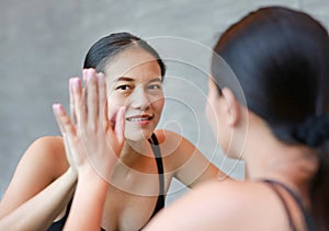 Face of smiling young asian woman looking at her reflection in mirror