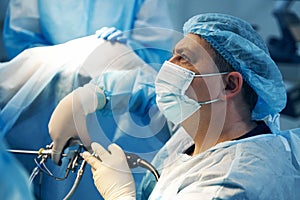 Face of surgeon in mask holding laparoscopic tool photo