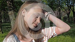 The face of a teenage girl with freckles. Beautiful girl face close-up. A girl on a sunny day outdoors adjusts her hair.