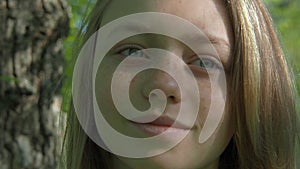 The face of a teenage girl with freckles. Beautiful girl face close-up. A girl on a sunny day outdoors adjusts her hair.