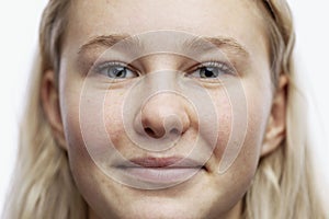 The face of a teenage girl with freckles. Cute smiling blonde. Young tender age. White background. Close-up