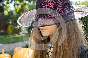 The face of a teenage girl in a witch hat close-up in backligh
