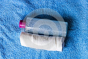 Face toner bottle and cotton pads on blue towel, applying facial toner using cotton pads concept