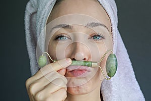 Woman using face roller for skin.