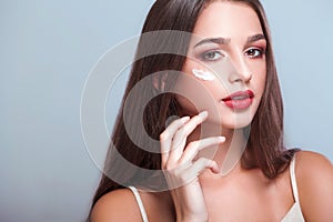 Face Treatment. Woman with healthy face applying cosmetic cream