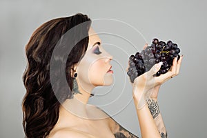 Face of a woman  with blue grapes