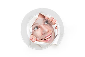 Face of woman peeking through a hole torn in white paper poster