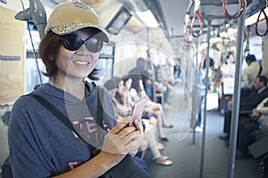 Face of woman in sky train with smart phone in hand use for city life and traveling theme