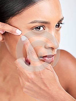 Face, woman and squeeze acne in studio of glowing spot, breakout or check dermatology on white background. Indian model