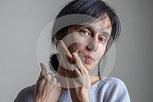 Face yoga, facial gymnastics, daily self care routine. Middle age caucasian woman performing facial exercises at home