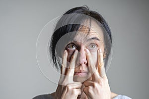 Face yoga, facial gymnastics, daily self care routine. Middle age caucasian woman performing facial exercises at home