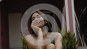 Face of a young and beautiful European brunette girl in a swimming suit close-up sitting near swimming pool touching the skin of