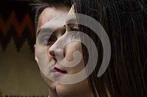 Face of young beautiful girl looking into the distance on the background face of the young guy, a couple in love