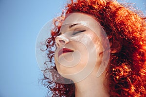 Face of young beautiful woman close-up. Female with curly, red hair, eyes closed