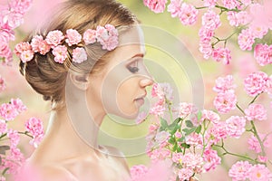 Face of young beautiful woman with pink flowers in her hair