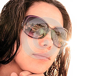 Face of young brunette girl in sunglasses with beach reflection